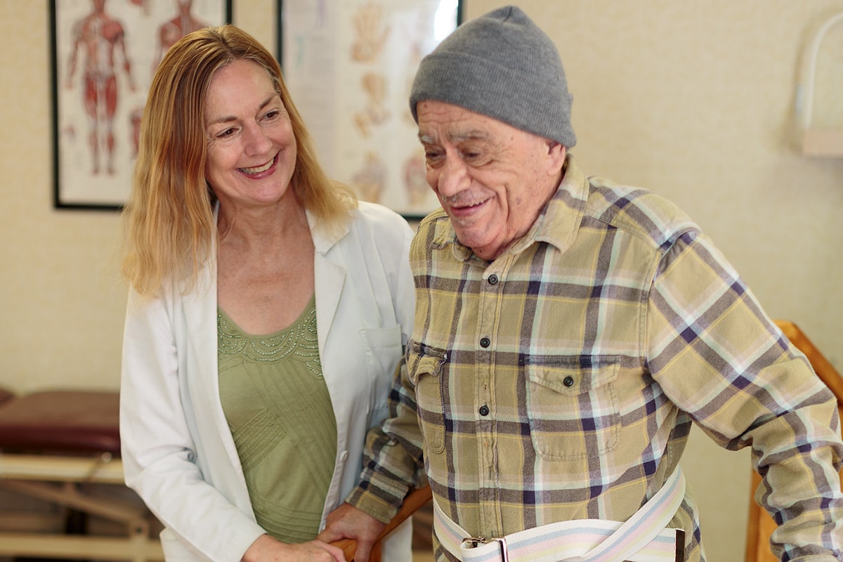 A rehab therapist with a resident in the rehab gym at Primrose Post-Acute